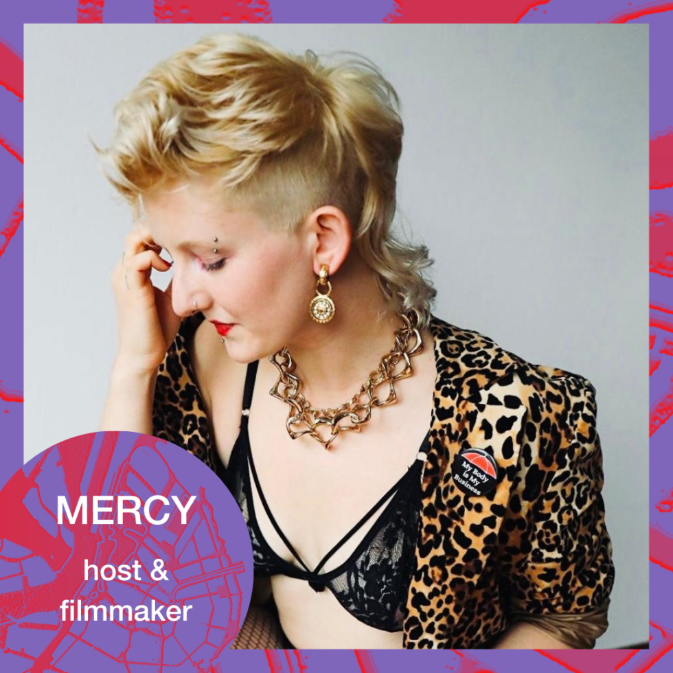 Photo of Mercy, host & filmmaker, with a mullet, gold jewelry, and leopard print jacket.