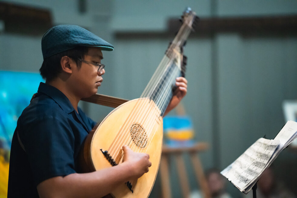Musician playing a lute, reading sheet music. Classic instrument performance.