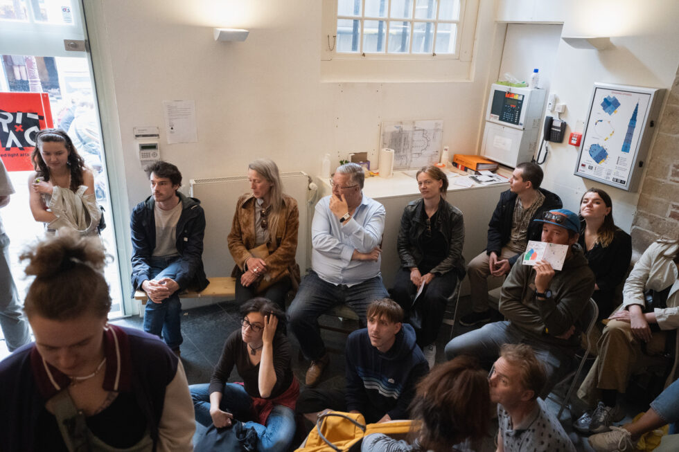 Group of people gathered indoors, listening attentively during a performance.