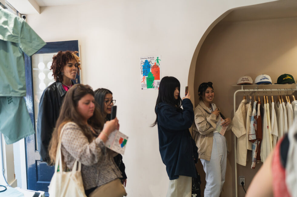People viewing art at Pop-in Culturele Dag event. Poster visible.