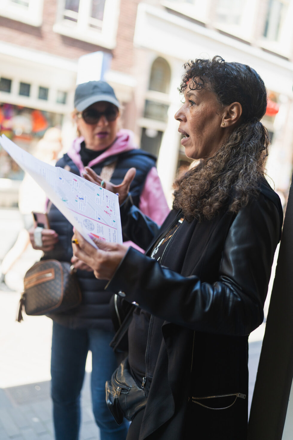 Woman with map giving walking tour directions, another woman behind her.