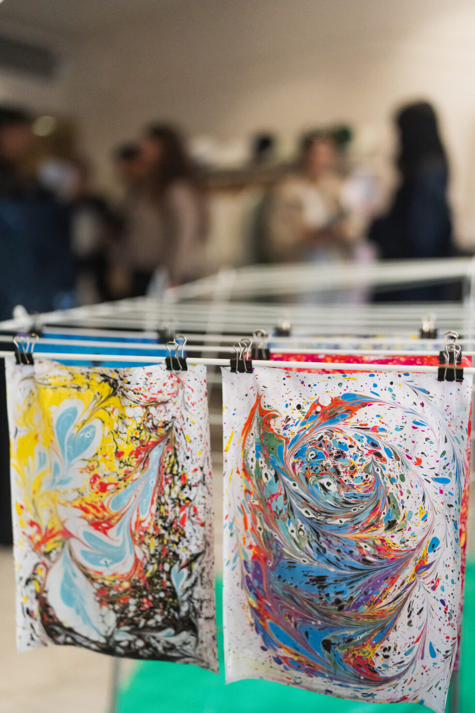 Marbled paper art drying on a rack, vibrant colors, abstract patterns.