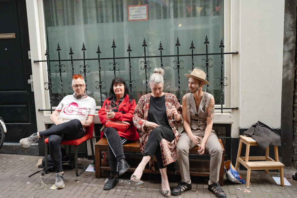 Four people sit outside a building in Amsterdam, one wearing a 