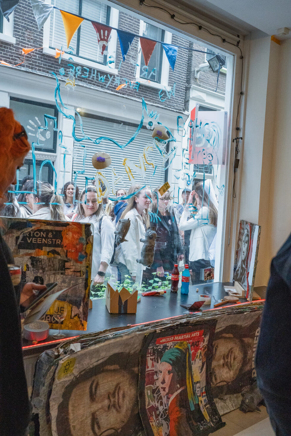 Group of people at an art exhibition, viewing art through a decorated window.