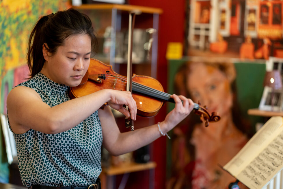 Woman playing the violin, focused on sheet music.