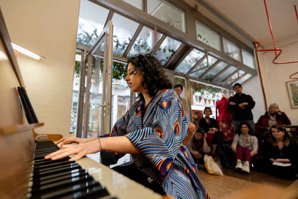 Woman playing piano in a room with an audience