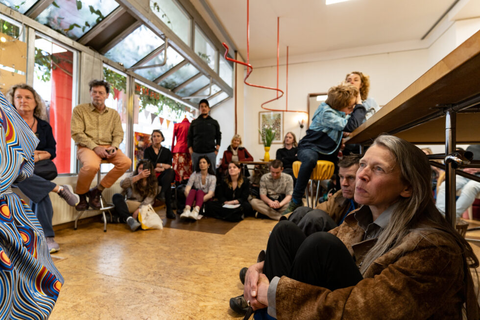 Audience at an indoor event, sitting and listening attentively.