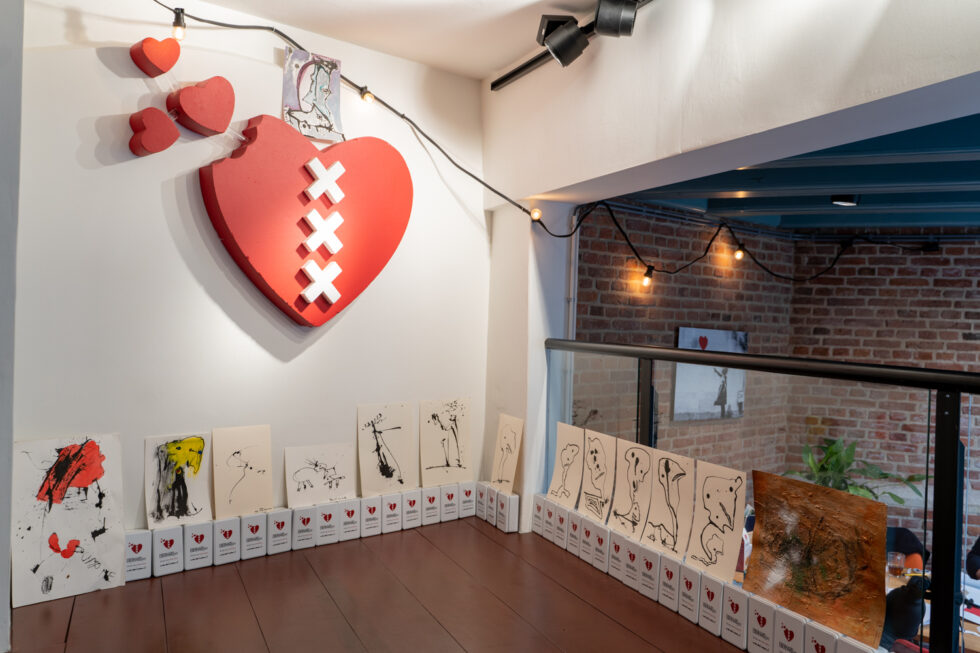 Large red heart art installation, Amsterdam-themed, with smaller art pieces below.