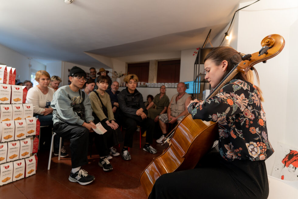 Cellist performing for a small audience in an intimate setting.
